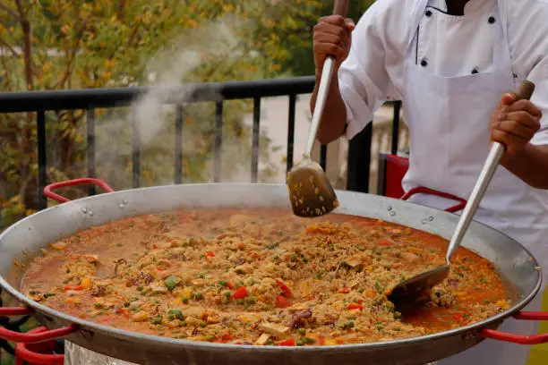 chef cooking Spanish paella in outdoor area