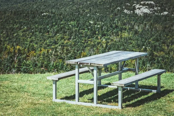 Picnic table on a mountain slope, with view over coniferous forest.