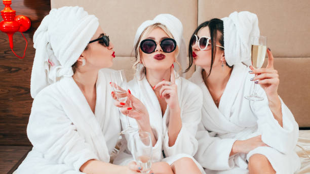 celebration spa congratulation women champagne Celebration party at spa. Friends congratulation. Young women with champagne. Sunglasses, bathrobes and turbans on. bride with friends stock pictures, royalty-free photos & images