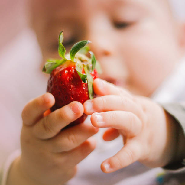 istock baby holding happy a red strawberry 1140684792