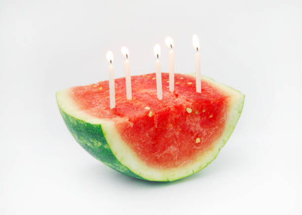 Closeup of lit birthday cake candles in a watermelon symbolizing healthy options for birthdays.