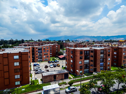 Panoramic of residential builings in Bogota with mountains in the background and cumulus clouds above