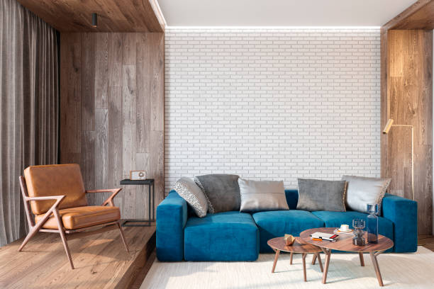 istock Modern living room interior with brick wall blank wall, blue sofa, leather lounge chair, table, wooden wall and floor, plants, carpet, hidden lighting. 3d render illustration mockup. 1140707046