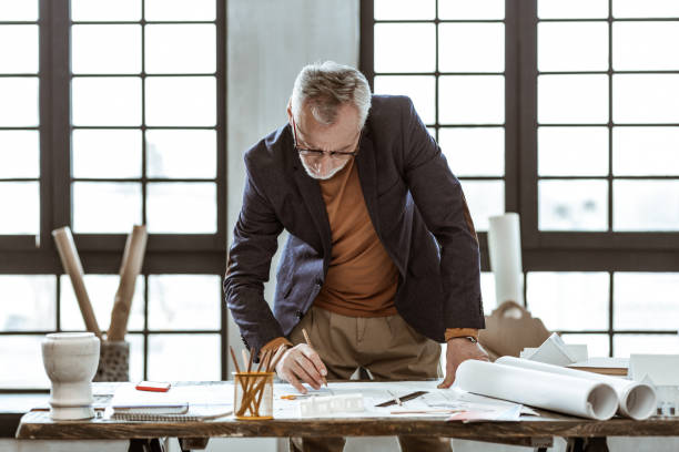 istock Interior designer wearing orange polo neck working on sketches 1140711118