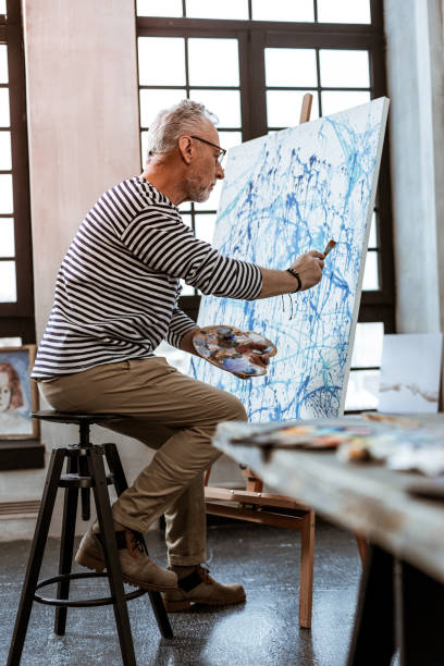 istock Artist holding painting brush while working on new canvas 1140711132