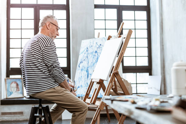 istock Bearded artist looking at white canvas and having creative ideas 1140711162