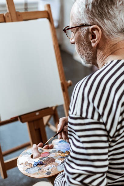 istock Creative bearded artist mixing some gouache while painting 1140711167