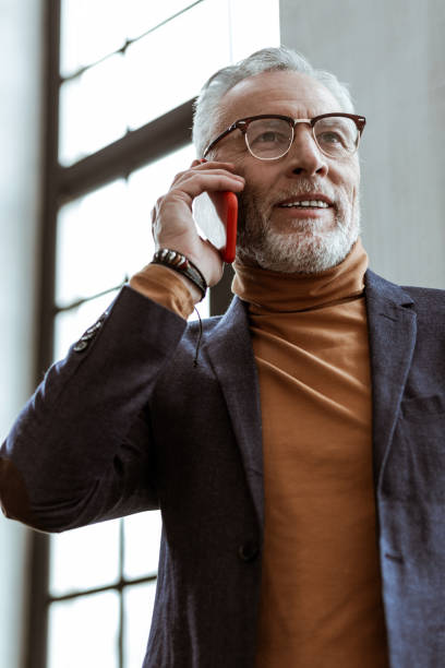 istock Bearded grey-haired man owning interior company calling client 1140713575