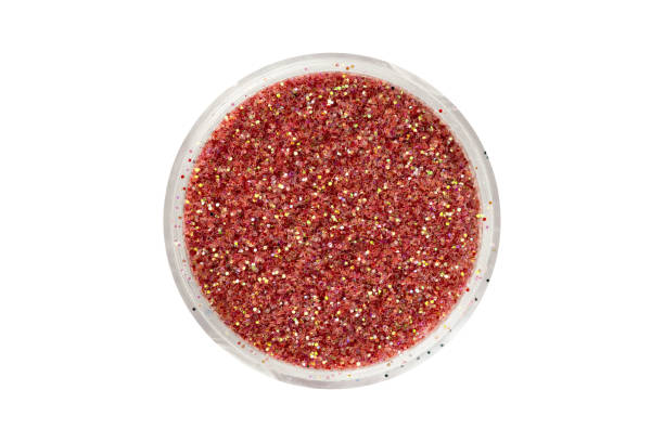 istock Brown red glitter particles in open container, view from above. Can be used for decorating nails or makeup. Beauty product isolated on white background, with clipping path 1140716874