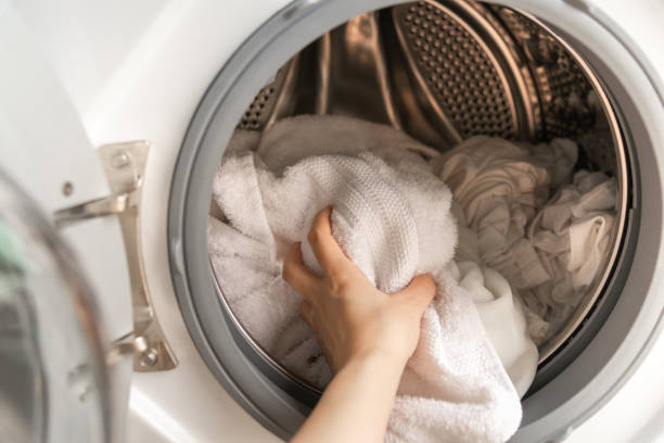 istock Close up of woman left hand loading white clothes into a washing machine. 1140722236