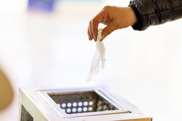 hand throwing white tissue paper in to a trash