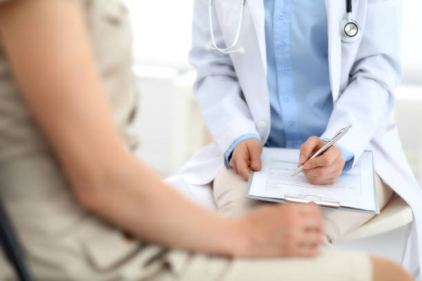istock Doctor and patient talking. Physician at work in hospital while writing up medication history records form on clipboard near sitting woman. Healthcare and medicine concepts 1140723310