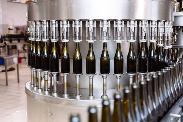 Glass bottles on the automatic conveyor line at the champagne or wine factory. Plant for bottling alcoholic beverages Glass bottles on the automatic conveyor line at the champagne or wine factory. Plant for bottling alcoholic beverages bottling plant stock pictures, royalty-free photos & images