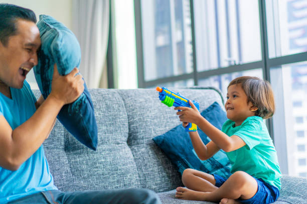 アジアのイスラム教徒のお父さんと息子は家族の時間を楽しんで。 - toy gun ストックフォトと画像