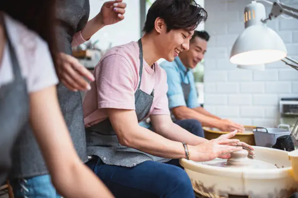 Photo of Young man shaping clay in a pottery class