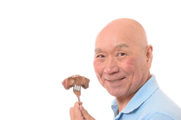 Smiling Japanese senior eating steak