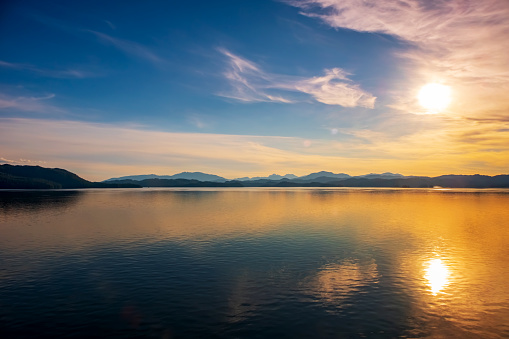 Sunset over water with mountain range in distance.