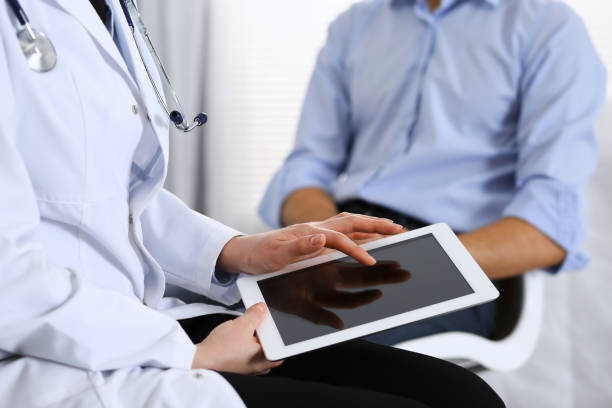 istock Female doctor using touchpad or tablet computer while consulting man patient in hospital. Medicine and healthcare concept 1140747557
