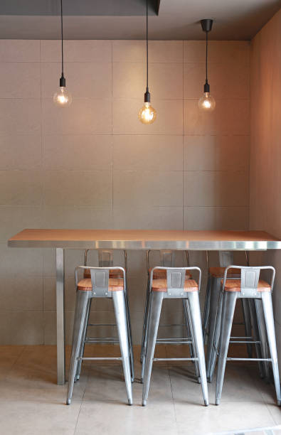 istock Modern table counter bar with chairs loft interior with gray tile wall and hanging decor lamps. 1140749776
