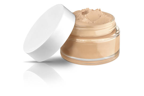 istock Nice glass face make-up creme foundation open container with a white plastic lid and smeared creme, isolated on white background and with reflections and shadows, clipping path included 1140750712