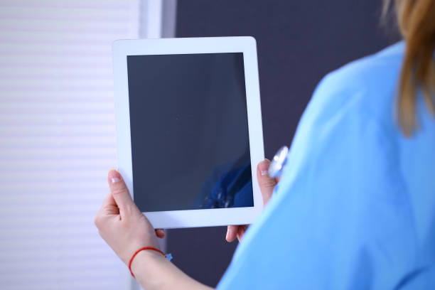 istock Woman doctor using tablet computer while standing straight in hospital office, closeup. Healthcare, insurance and medicine concept 1140751127