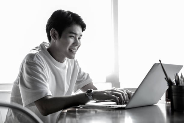 Young Asian Man Happily Working In The Office On His Laptop Computer