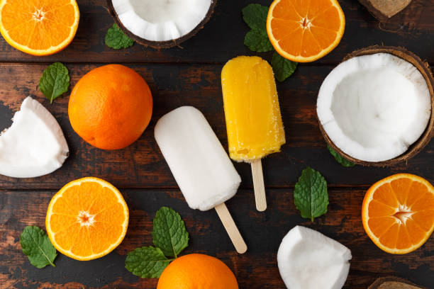 Homemade Coconut, Orange popsicles, ice lolly, on wooden table. Summer food.