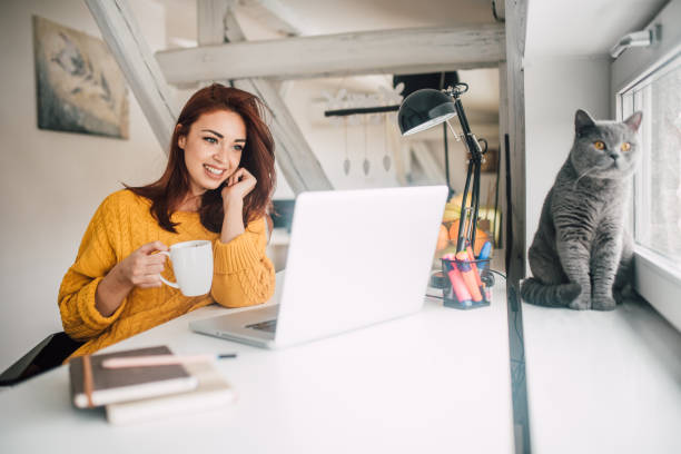 istock Woman holding a cup of coffee and using laptop 1140762840