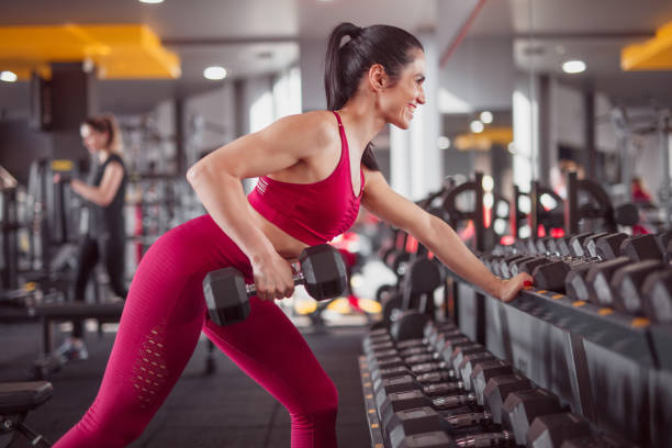 istock Smiling woman doing dumbbell row in gym 1140764325