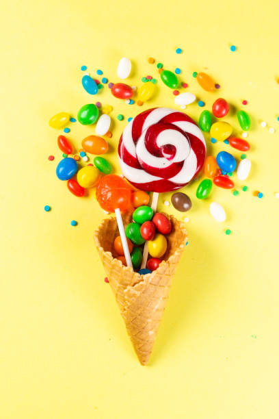 istock Lollopops and candies in ice cream cone on bright yellow background 1140774720