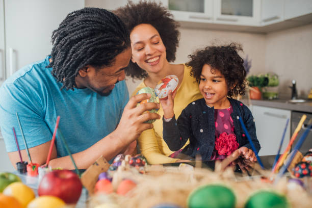 pareja decorando huevos de pascua con su hija - vacations two generation family holiday easter fotografías e imágenes de stock