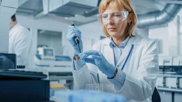 o cientista de pesquisa fêmea usa a micro pipeta ao trabalhar com tubos de teste. povos no laboratório farmacêutico inovativo com equipamento médico moderno para a pesquisa da genética. - dna laboratory research science - fotografias e filmes do acervo