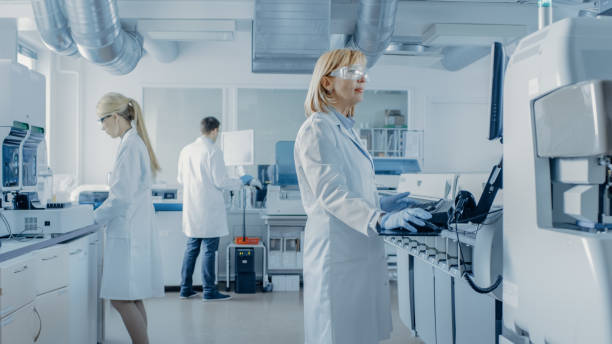 의료 장비를 사용 하 여 컴퓨터에서 작업 하는 연구 과학자 팀은 현대 실험실에서 특수 기계로 혈액 및 유전 물질 샘플을 분석 합니다. - 진료소 이미지 뉴스 사진 이미지
