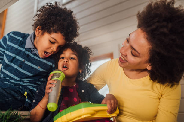 Woman singing karaoke with children Young kids having fun singing karaoke with their other traditional song stock pictures, royalty-free photos & images