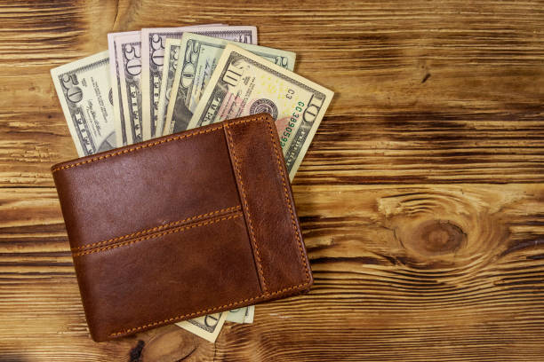 istock Brown leather wallet and american dollars on wooden table. Top view 1140782822