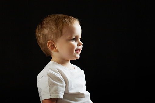 Portrait of a child in profile on a black background. Boy looking forward, concept, copy space right