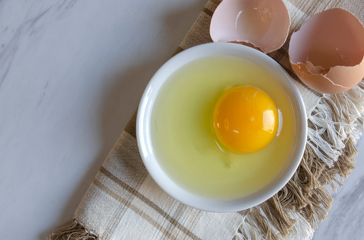 Broken egg showing egg white and yolk.  Horizontal view with copy space.  Promoting ethical farming, cooking, Easter, healthy eating and free range chickens.