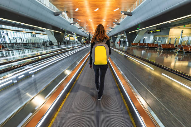 mujer viajero con mochila ir en movimiento pasarela travolator en el nuevo aeropuerto internacional de hamad - cinta mecánica fotografías e imágenes de stock