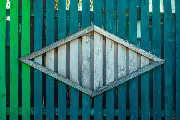 Texture of old fence, painted light-green and blue with rhombus from wood in the center. Horizontal texture