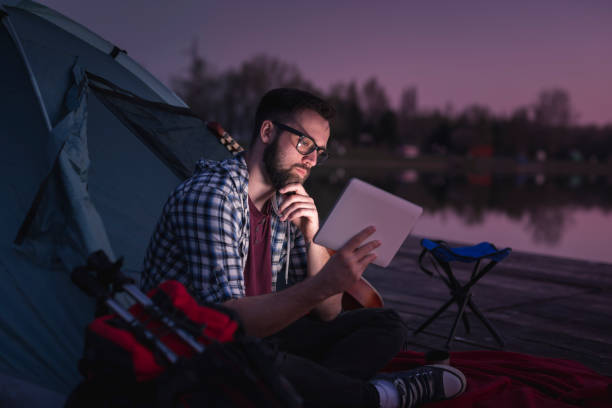 un hombre acampando junto al lago - hipster people surfing the net internet fotografías e imágenes de stock