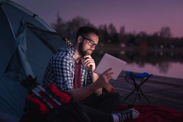 man camping by the lake - hipster people surfing the net internet imagens e fotografias de stock