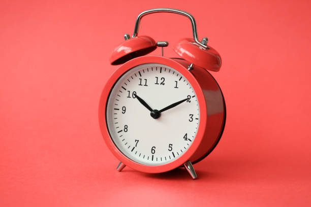 istock Coral old alarm clock on red background 1140797265