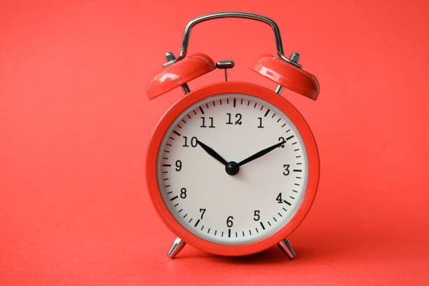 istock Coral old alarm clock on red background 1140797268