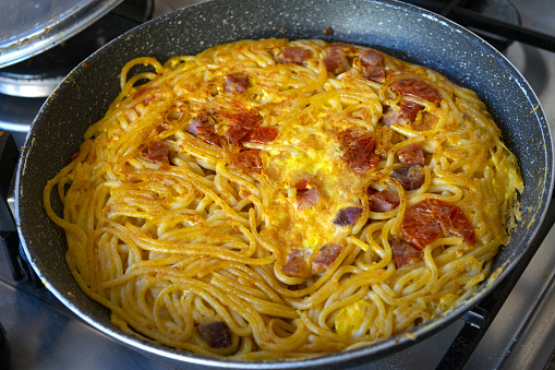 spaghetti frittata in pan with fresh cherry tomatoes