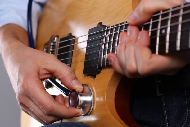 istock Male arms hold stethoscope head diagnosing guitar 1140798317