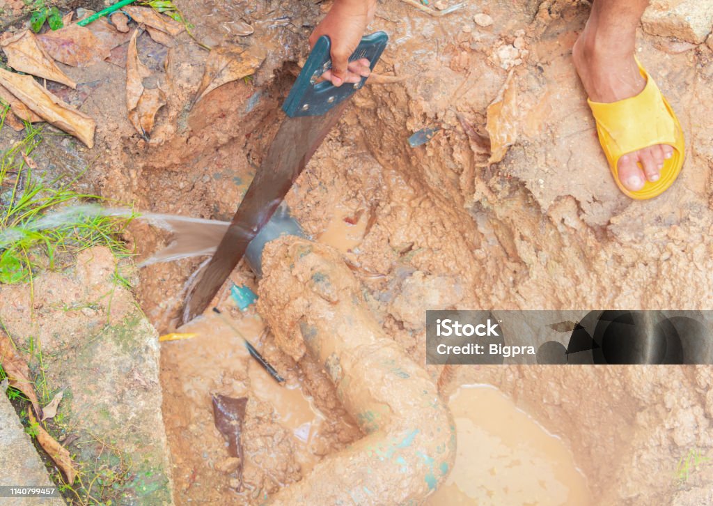 broken pipe in hole and water motion at roadside  plumber working repair and saw On the floor soil with cut saw Adult Stock Photo