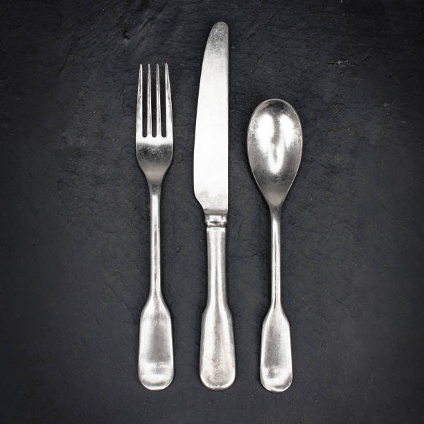 istock Set of silver fork, knife and spoon on black slate serving board. 1140800750