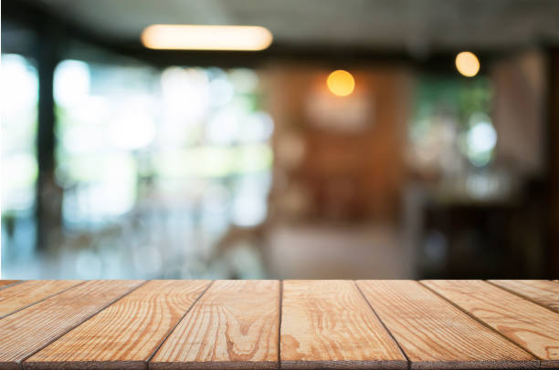 istock empty wooden desk over blurred coffee shop background 1140801024