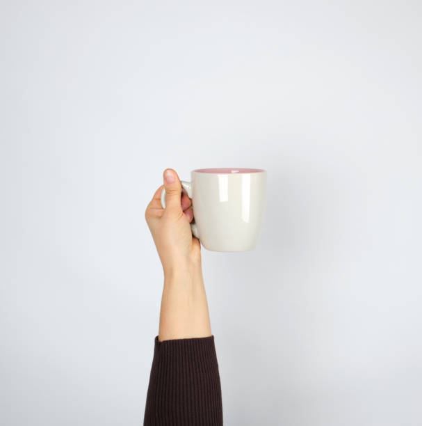 istock gray ceramic cup in female hand on a white background, hand raised up 1140803409