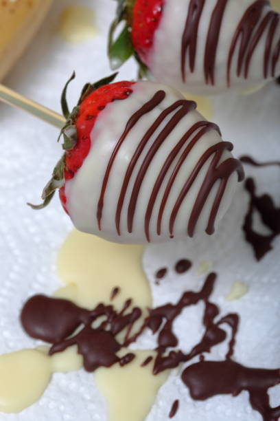 istock Strawberries glazed in black and white chocolate dries on a plate. On the work surface visible drops of chocolate. Cooking strawberries glazed in chocolate. 1140817787